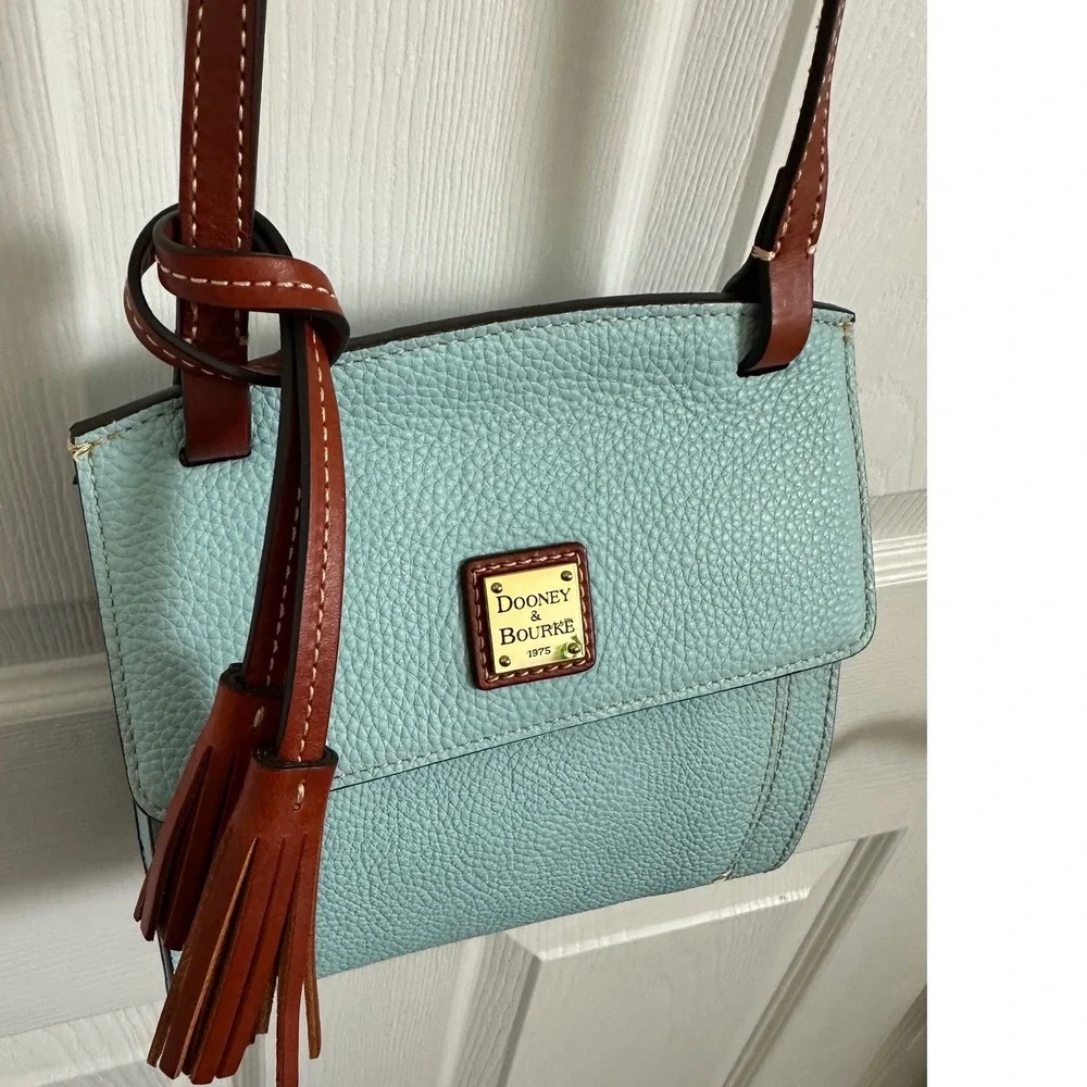 This is a Dooney & Bourke Pebble Grain East/West Flap Crossbody in a light blue
